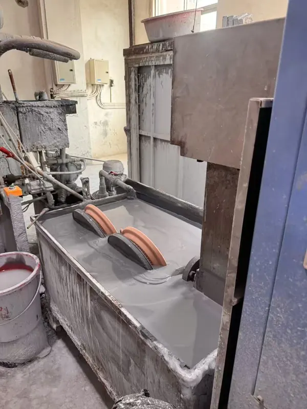 Pieces pass through the glaze tank before the kiln.